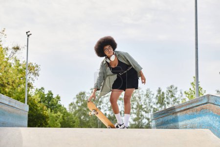 A young African American woman with curly hair confidently skateboards in a sleek black dress at a vibrant outdoor skate park.
