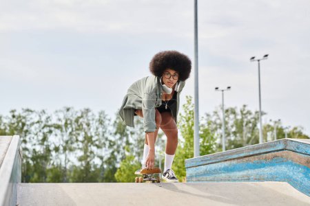 Young African American woman with curly hair skilfully rides a skateboard on a ramp at an outdoor skate park.