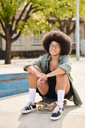 A stylish young African American woman with a voluminous afro hairdo leisurely sits on a skateboard at a vibrant skate park.