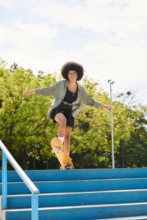 A young African American woman with curly hair skateboards down an urban flight of stairs in a skate park.