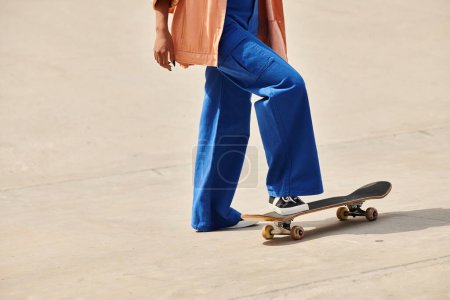 Young African American woman skillfully skateboarding on a cement surface at a skate park.