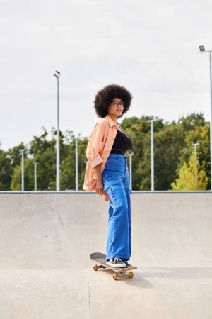 A young African American woman with curly hair confidently stands on a skateboard at a vibrant skate park.