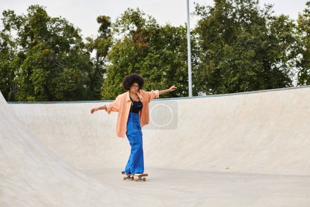 Photo for A young African American woman with curly hair confidently rides her skateboard up the side of a ramp in a skate park. - Royalty Free Image