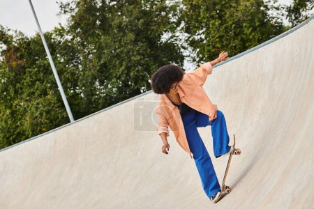 Photo for A daring man rides a skateboard up the side of a ramp in an impressive display of skill and courage at the skate park. - Royalty Free Image