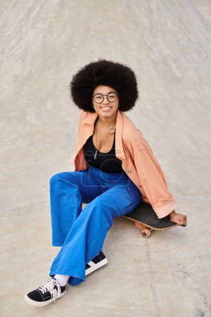 A stylish young African American woman with an afro hairdo sitting confidently on a skateboard at a vibrant skate park.