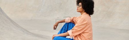 Téléchargez les photos : Une jeune afro-américaine aux cheveux bouclés s'assoit en toute confiance sur une planche à roulettes dans un skate park urbain animé. - en image libre de droit