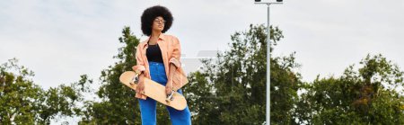 Photo for A young African American woman with curly hair gracefully stands on a skateboard in a vibrant park setting. - Royalty Free Image