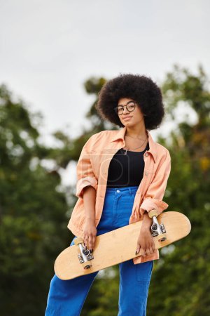 A stylish African American woman with an afro hairdo confidently holds a skateboard in a vibrant skate park setting.
