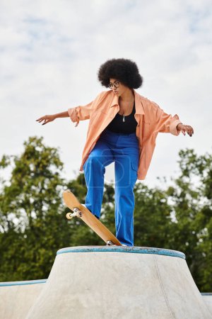 Una joven afroamericana con el pelo rizado monta un monopatín encima de una rampa de cemento en un parque de skate al aire libre.