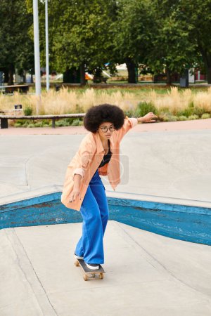 Young African American woman with curly hair rides skateboard down cement ramp at outdoor skate park.