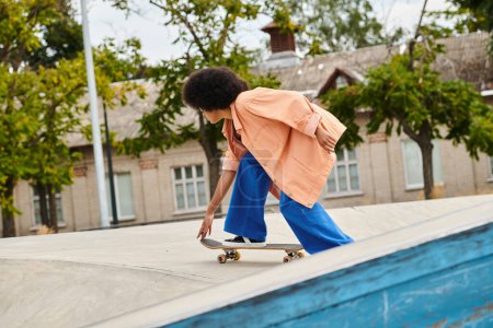 Photo for Young African American woman with curly hair skateboarding on a ramp at an outdoor skate park. - Royalty Free Image