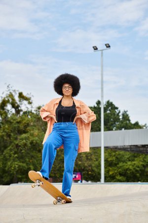 A young African American woman with an afro rides a skateboard in a vibrant outdoor skate park.