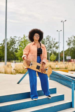 A young African American woman with curly hair confidently holds a skateboard while standing on steps outdoors.