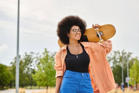 Una joven afroamericana con el pelo rizado sostiene un monopatín hasta la cara en un parque de skate.