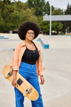 An energetic young African American woman holds a skateboard while surrounded by the urban setting of a lively skate park.