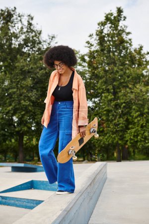 A young African American woman with curly hair stands confidently on a ledge with her skateboard in a skate park.