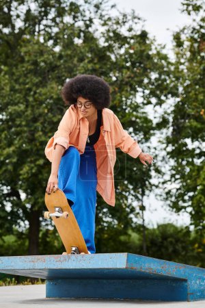 A young African American woman with curly hair, wearing blue pants and an orange shirt, executes a trick on a skateboard at a vibrant skate park.