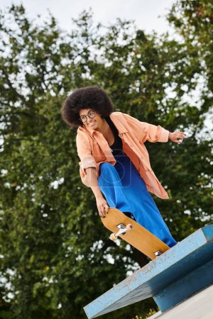 Téléchargez les photos : Femme noire glisse sans effort vers le bas d'une rampe de planche à roulettes avec compétence et précision, mettant en valeur le mouvement audacieux. - en image libre de droit