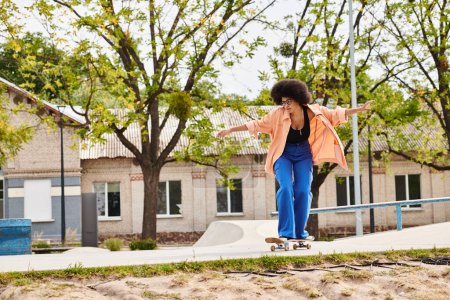 A young African American woman with curly hair gracefully rides a skateboard down a sidewalk in a skate park.