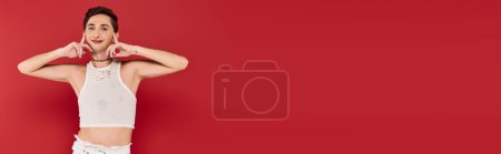 Photo for Joyful gay man with stylish accessories in white attire looking at camera on red backdrop, banner - Royalty Free Image