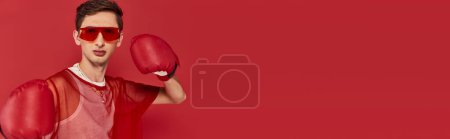 alluring gay man with sunglasses and red fishnet with boxing gloves and looking at camera, banner