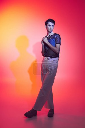 Photo for Appealing androgynous fashionista with accessories in casual attire posing and looking at camera - Royalty Free Image