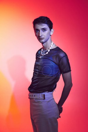 Photo for Handsome androgynous fashionista with accessories in casual attire posing and looking at camera - Royalty Free Image