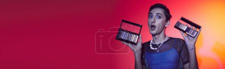 Photo for Chic gay man in cozy attire using eyeshadows palette and looking at camera on vivid backdrop, banner - Royalty Free Image