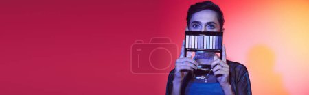 Photo for Chic gay man in cozy attire using eyeshadows palette and looking at camera on vivid backdrop, banner - Royalty Free Image