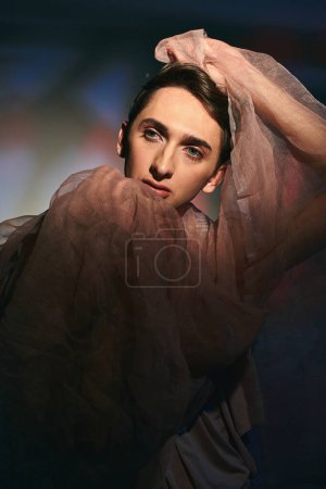 Photo for Chic well-dressed androgynous man in pastel elegant clothes looking away on vibrant backdrop - Royalty Free Image