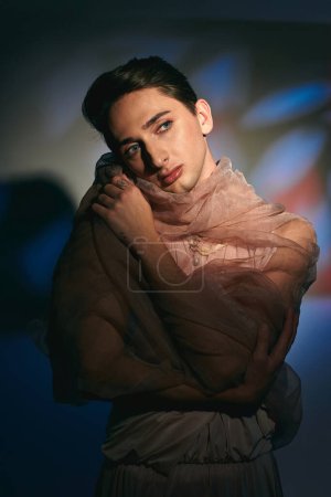 Photo for Chic sophisticated androgynous man in pastel elegant clothes looking away on vibrant backdrop - Royalty Free Image