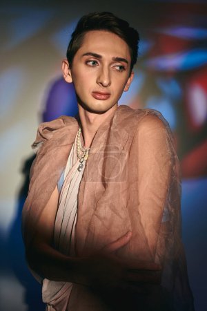 Photo for Chic sophisticated androgynous man in pastel elegant clothes looking away on vibrant backdrop - Royalty Free Image