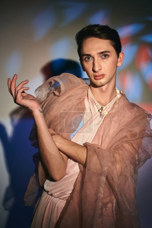 Photo for Sophisticated androgynous fashionista in pastel attire looking at camera on vibrant backdrop - Royalty Free Image