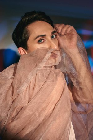 Foto de Elegante andrógino fashionista con el pelo oscuro en traje de pastel mirando a la cámara en el fondo vívido - Imagen libre de derechos