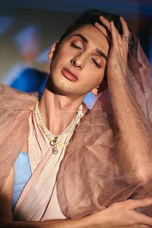 Téléchargez les photos : Belle fashionista androgyne aux cheveux foncés en tenue élégante pastel posant les yeux fermés - en image libre de droit