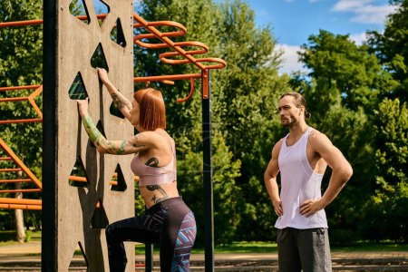 A determined woman, guided by their personal trainer, conquer a climbing wall in sportswear.