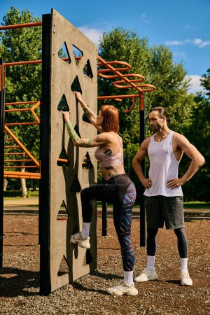 A woman in sportswear, guided by a personal trainer, climbing a rock wall, showcasing determination and motivation.