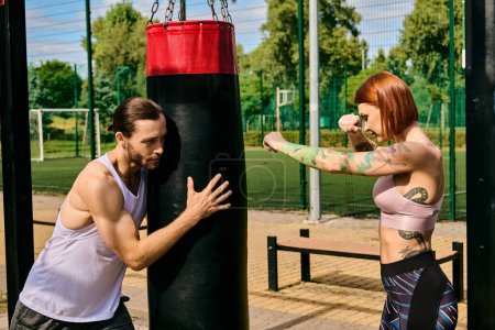 Una mujer en ropa deportiva se dedica a un entrenamiento de boxeo en un parque, guiada por un entrenador personal, mostrando determinación y motivación.