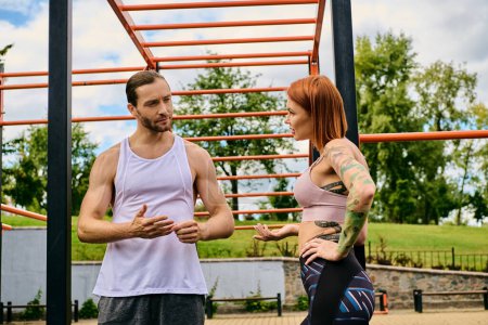 A woman in sportswear, guided by a personal trainer, display determination and motivation as they exercise outdoors together.