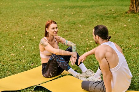 Téléchargez les photos : Une femme, vêtue de vêtements de sport, s'engage dans une séance d'entraînement guidée par un entraîneur personnel sur un tapis dans le parc. - en image libre de droit