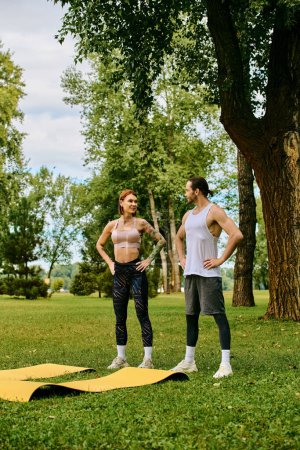 A woman in sportswear stand engaged in a fitness routine with personal trainer in a serene park setting.