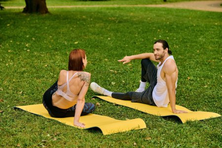 A man and woman in sportswear practice yoga in a peaceful park, guided by personal trainer, embodying determination and motivation.
