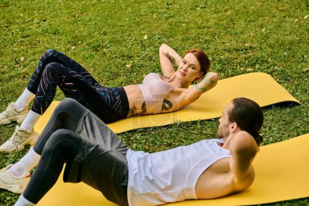 Ein Personal Trainer führt eine entschlossene Frau in Sportbekleidung bei Yoga-Übungen auf Matten im Freien.