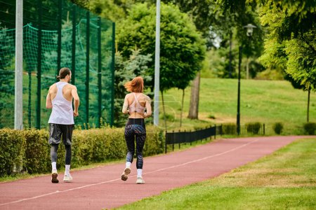Un hombre y una mujer en ropa deportiva están corriendo por un camino con determinación.