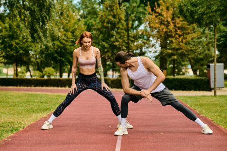 Un hombre y una mujer decididos, vestidos con ropa deportiva, realizando un ejercicio de estiramiento