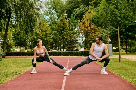 determined woman and man in sportswear stretching, showing dedication to their outdoor workout.