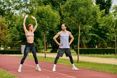 Un hombre y una mujer decididos en ropa deportiva, entrenan juntos en una pista, mostrando motivación y trabajo en equipo.