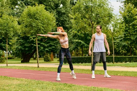A man and a woman in sportswear stretching outdoors, showing determination and motivation.