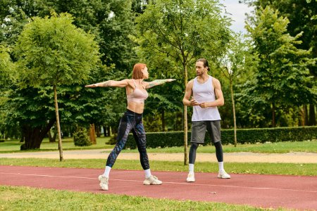 Photo for A man and a woman in sportswear stretching outdoors, showing motivation. - Royalty Free Image