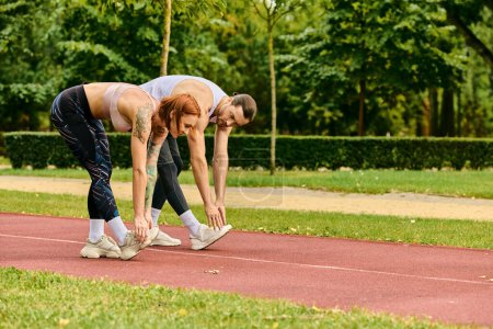 A man and woman, dressed in sportswear, train together on a track, displaying determination and motivation.